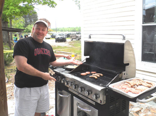 Mark, son-in-law of the farm’s owner, prepares lamb burgers and brats for tour visitors.