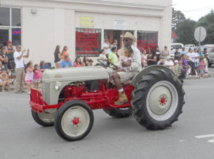 Young and old are part of the parade of tractors.