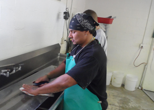 Roosevelt Jones cleans croaker for a waiting customer.