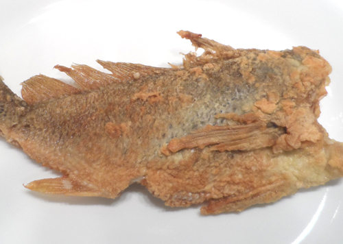 Cooked croaker is ready for a side to be added onto the plate.