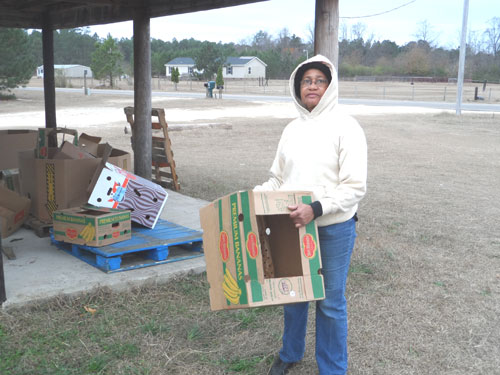 Volunteer Geneva Gillis prepares boxes that will be used by families tolunteer preparing boxes for families to take home sweet potatoes.