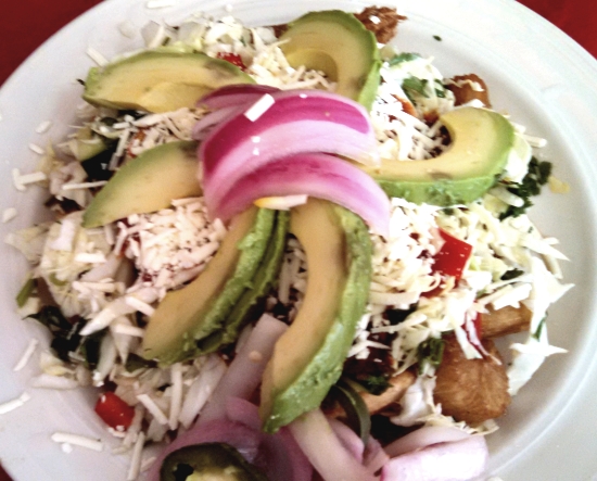 Yuca con Chicharron: Fried or steamed yuca served with chicharrones, cabbage salad, tomato sauce, chismol and pickled vegetables. 