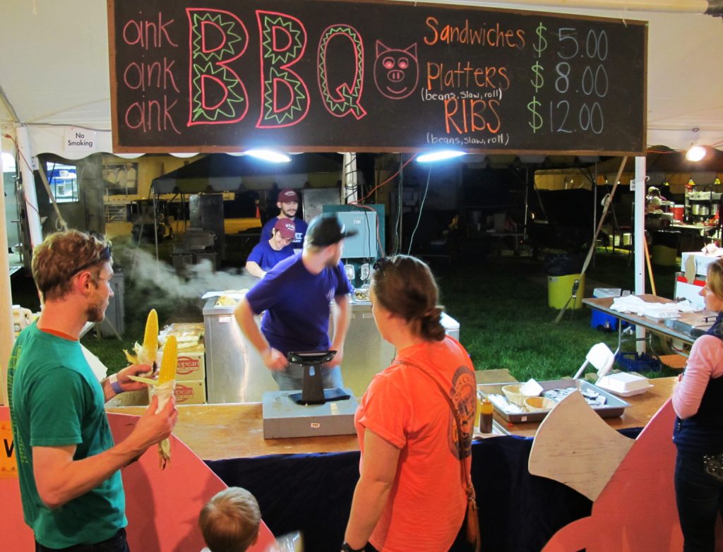 A family with corn on the cob at the Wilkes Community College culinary program BBQ booth.